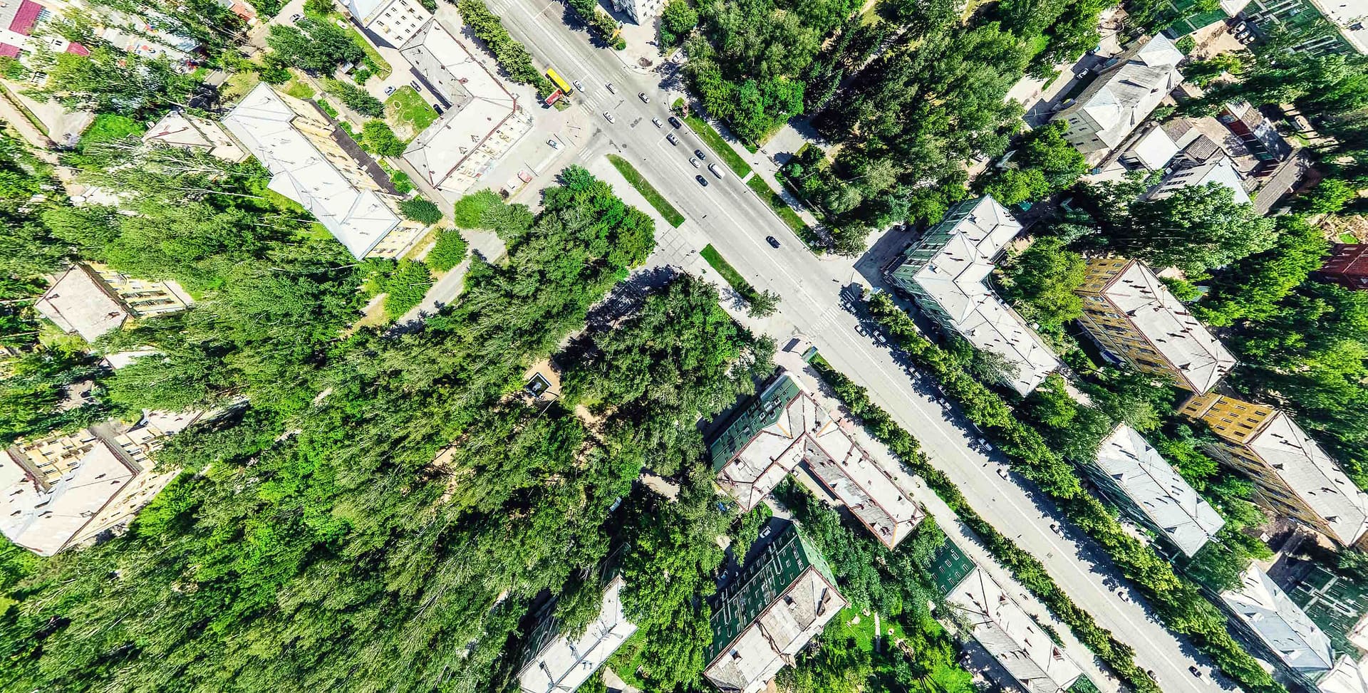 Aerial city view with crossroads and roads, houses, buildings, parks and parking lots, bridges. Helicopter drone shot. Wide Panoramic image.