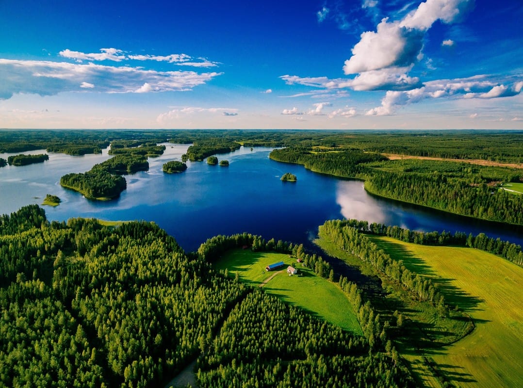 Aerial view of blue lakes and green forests on a sunny summer day in Finland.